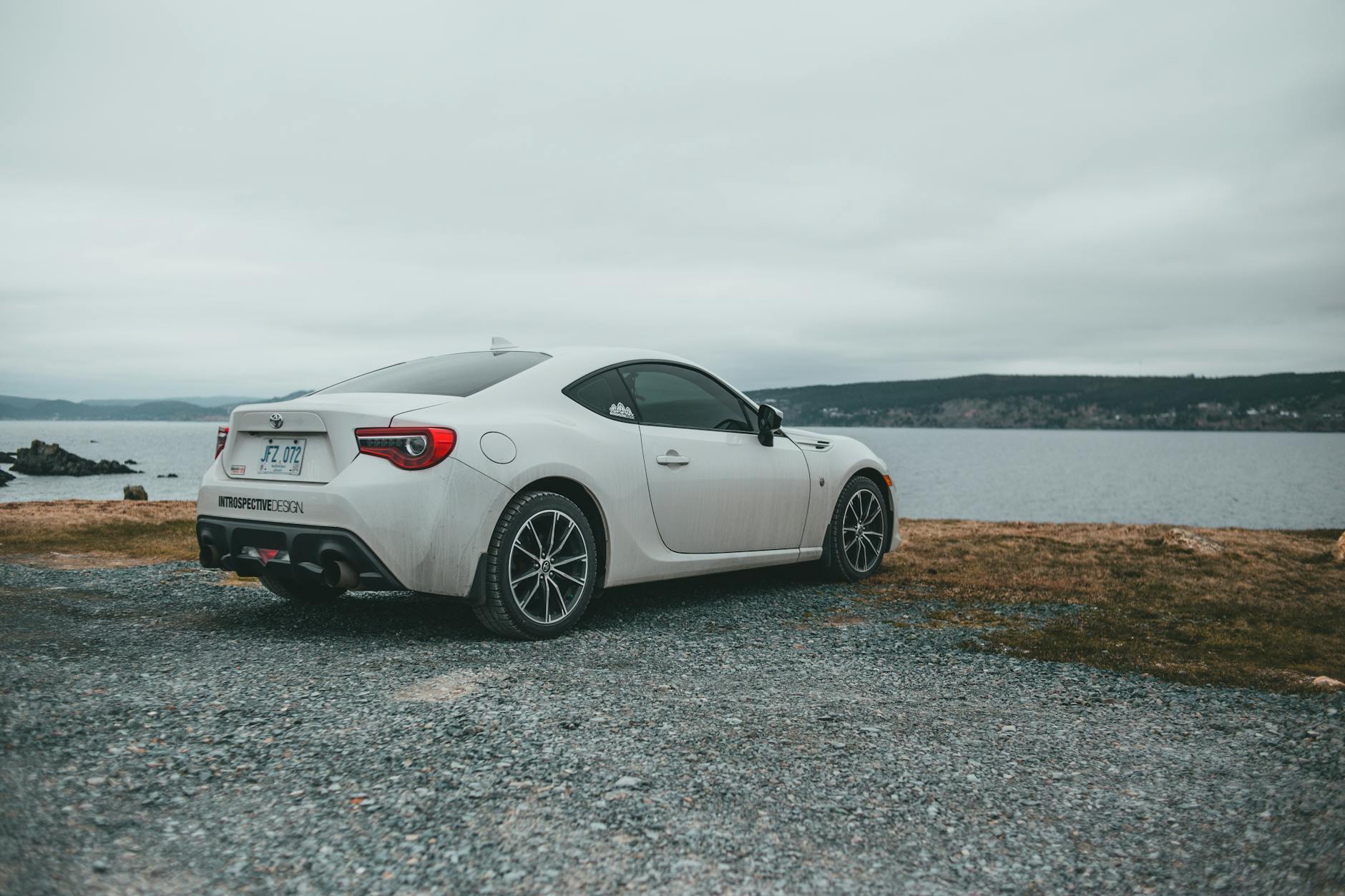 Białe luksusowe coupé zaparkowane nad jeziorem przy pochmurnym niebie