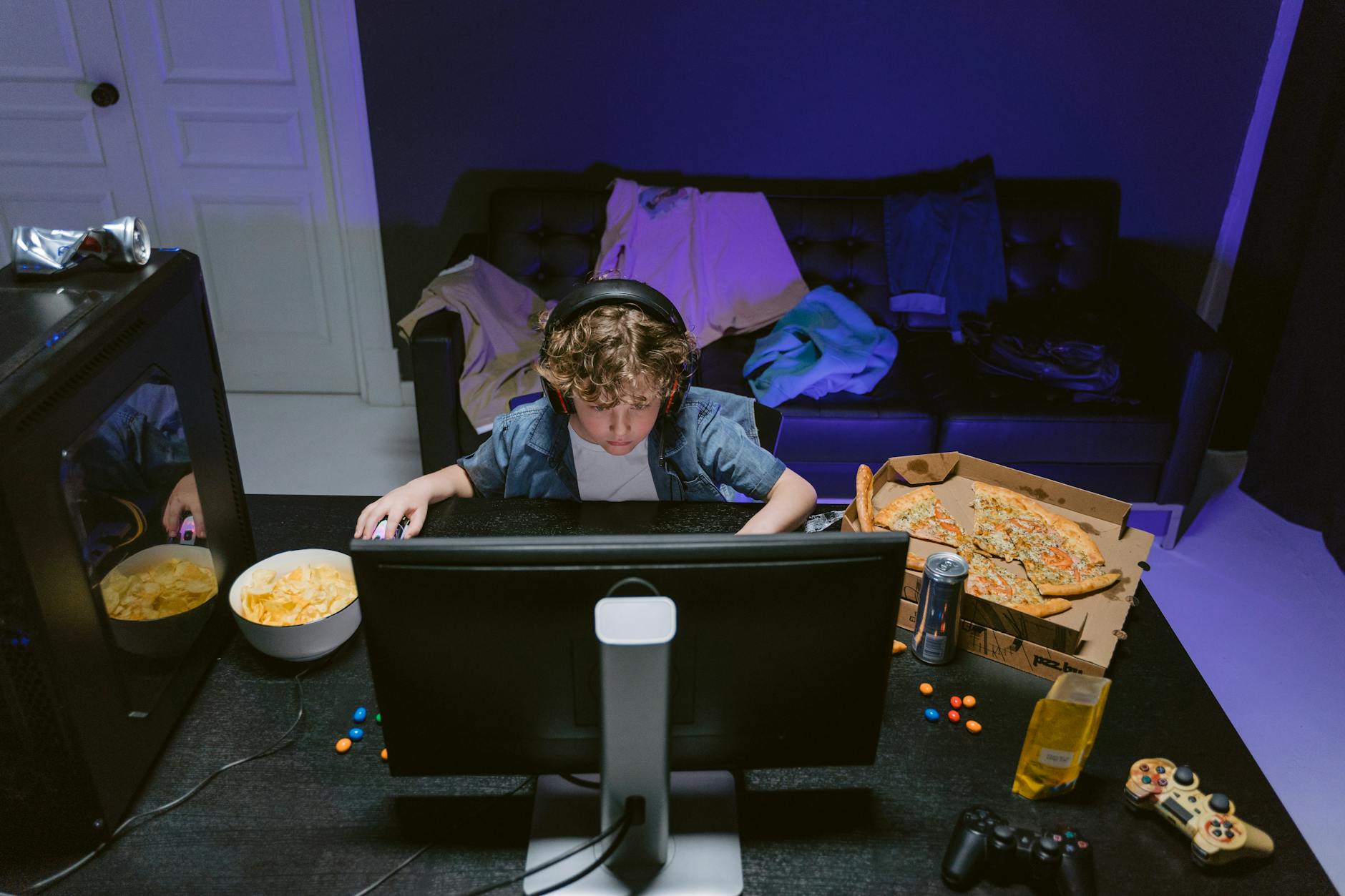 Chłopiec gra w GTA Online w domu, na biurku przekąski i napoje