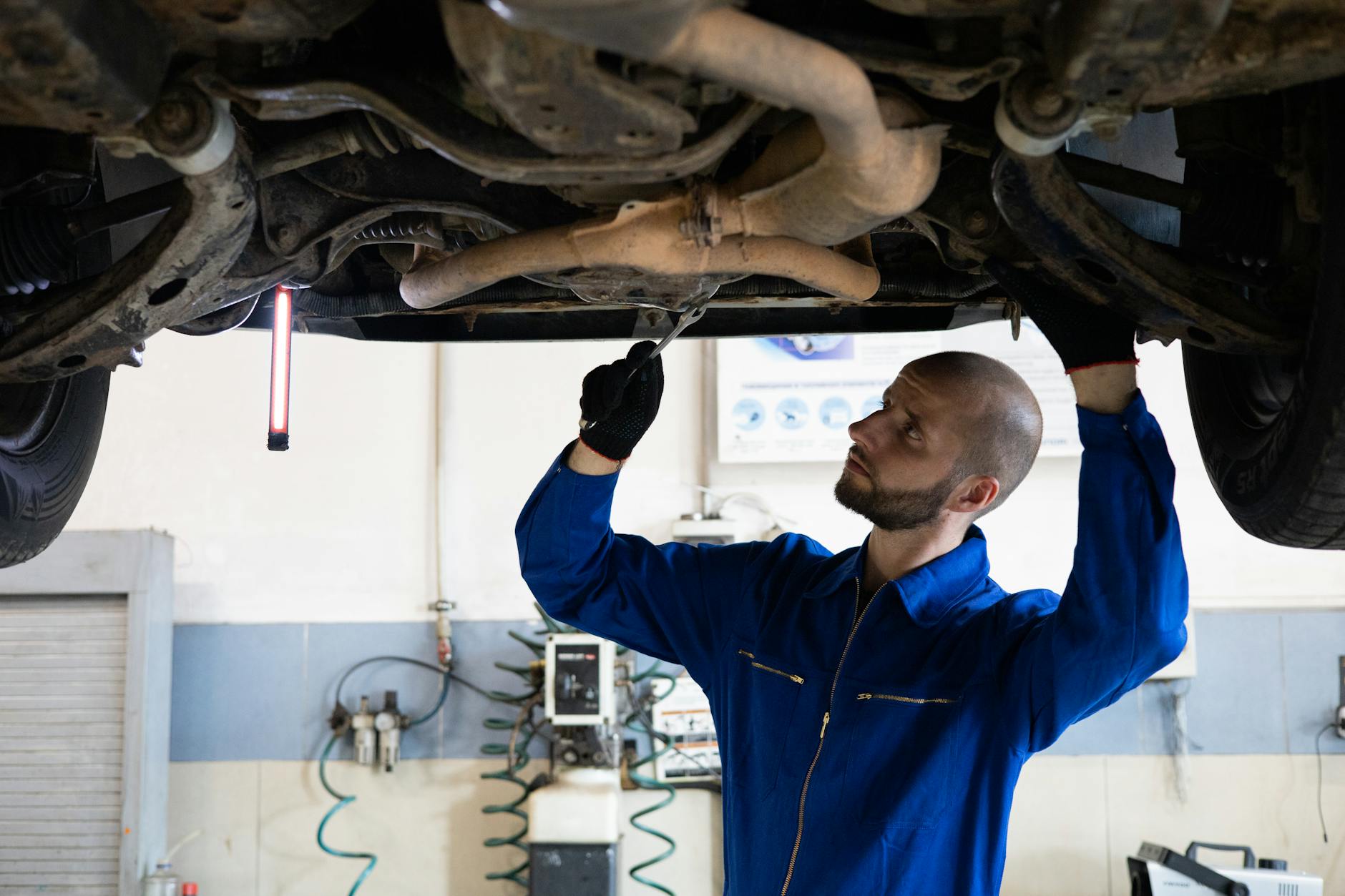 Mechanik w niebieskim kombinezonie sprawdza układ wydechowy Toyoty w warsztacie