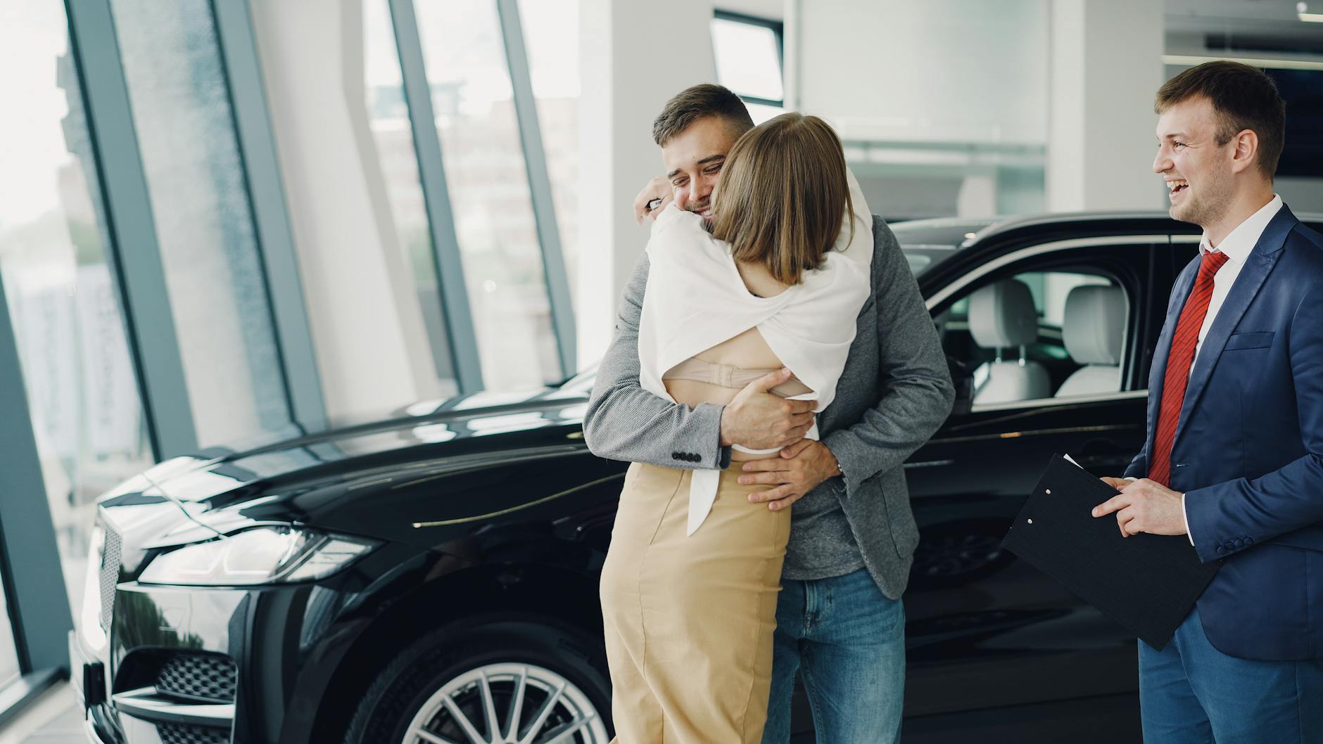Para szczęśliwie obejmuje się przy nowo kupionym Maserati w salonie