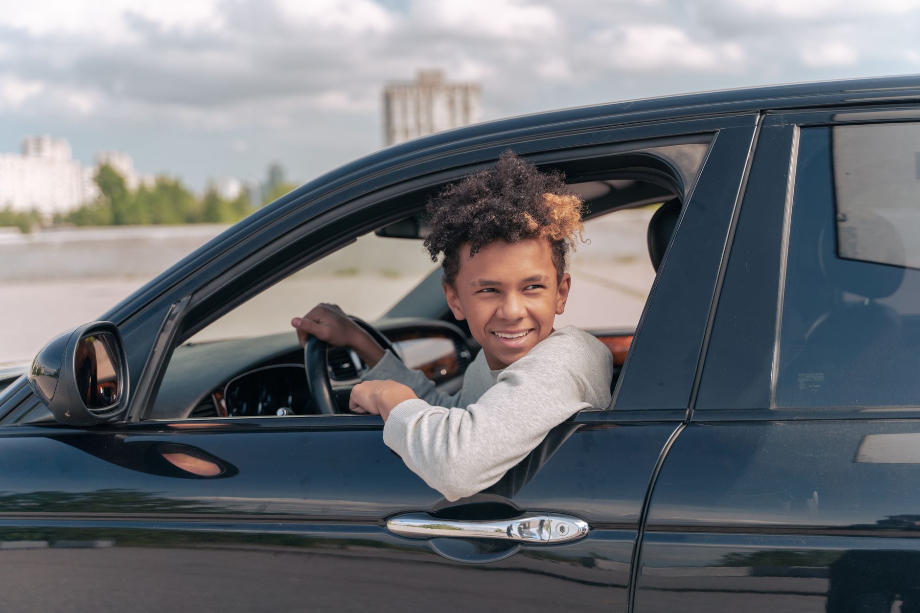 Młody kierowca z kręconymi włosami uśmiecha się za kierownicą Chevroleta