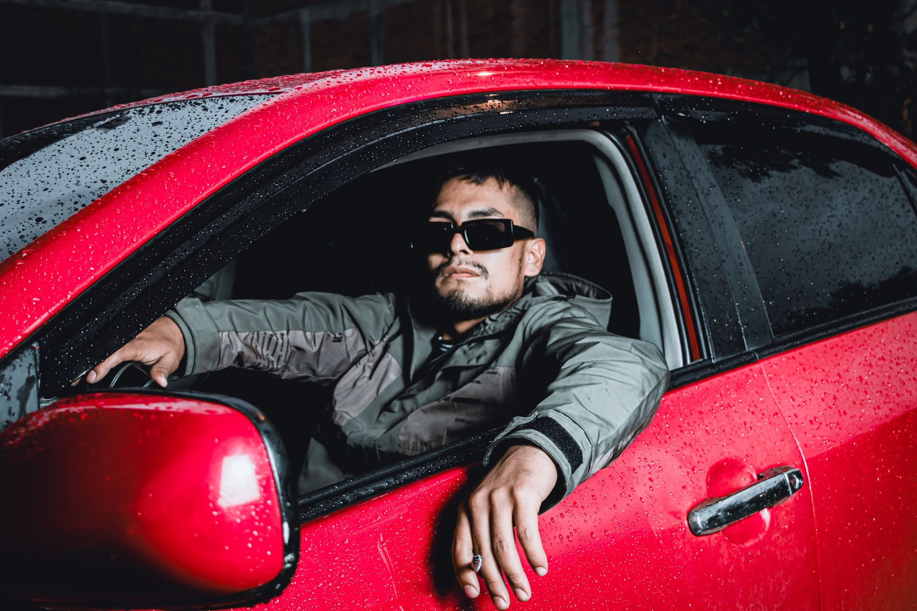 Młody mężczyzna w okularach przeciwsłonecznych siedzi w czerwonym Chevrolecie no