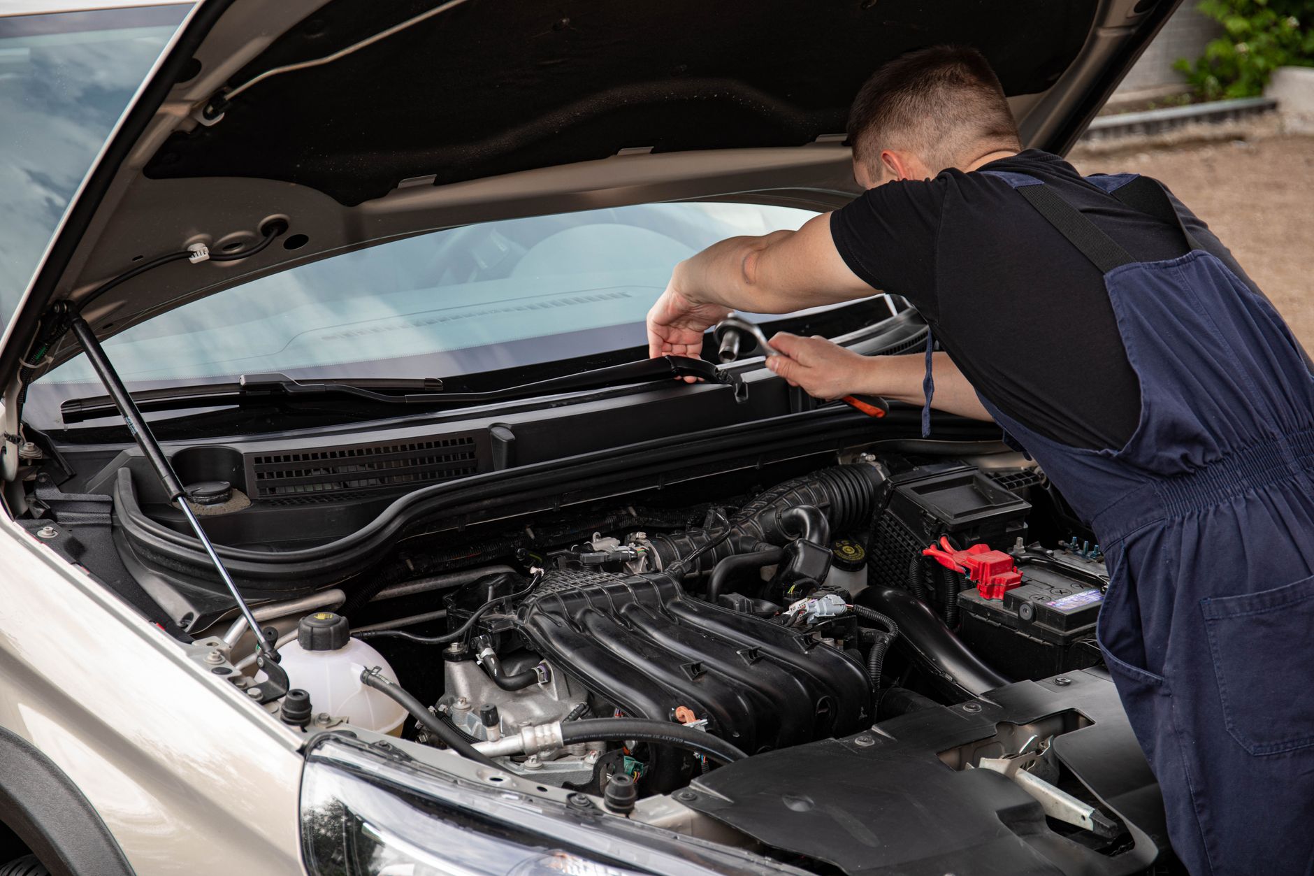 Mechanik naprawia silnik samochodu Ford na zewnątrz w ciągu dnia