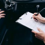 Dłonie wypełniające formularz ubezpieczenia Porsche wewnątrz auta